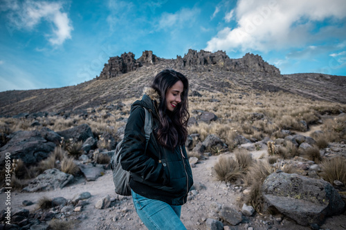 Explorer girl smiling in the middle of the adventure in the mountains, wearing winter clothes, behind them you can see the mountains and the winter snow photo