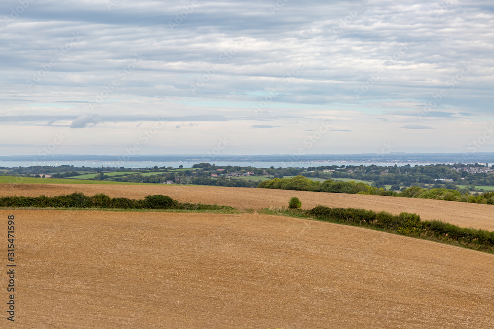 Looking out from a hilltop over farmland towards the coast, on the Isle of Wight