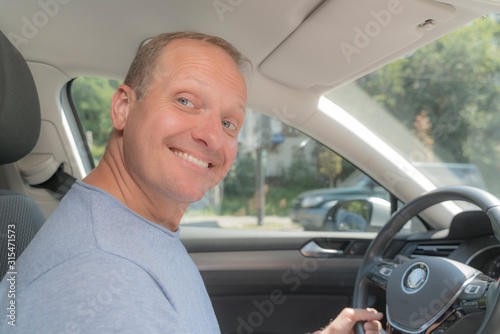 Portrait of happy owner of new automobile. Blond man took out an insurance policy for his new car, feel joy and smiling. Soft color image, horizontal and close-up. © Lana