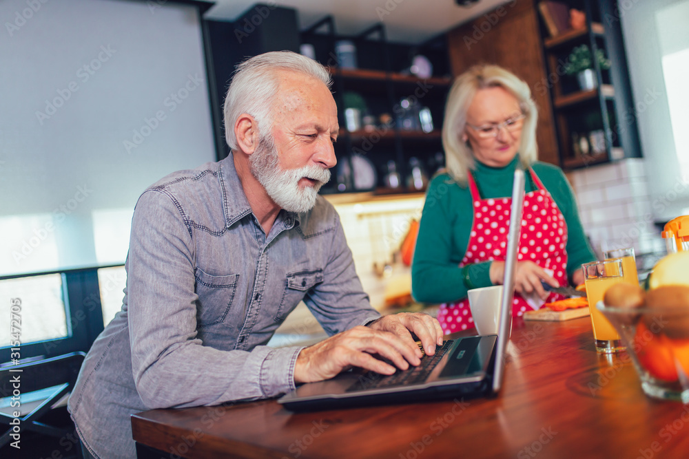 Happy retired couple browsing the internet together on a laptop computer.