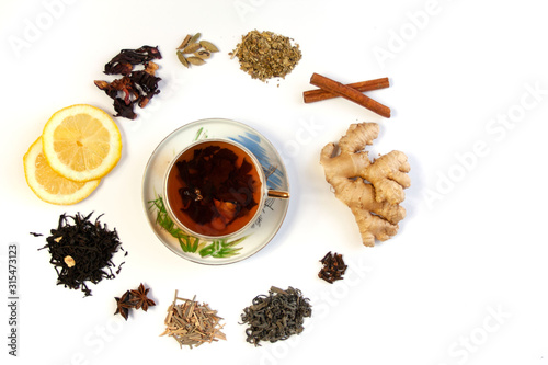  Filiżanka z herbatą otoczona różnymi gatunkami herbat oraz rozgrzewającymi leczniczymi przyprawami i dodatkami do herbaty