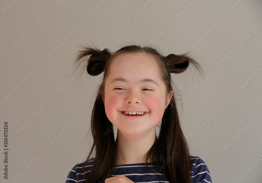 Cute smiling down syndrome girl on the grey background Stock Photo ...