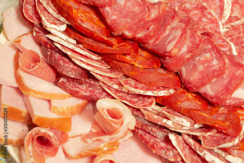 Antipasti composition of italian cured meat types. Salami, ham and dry sausage slices, closeup. Food background, texture and wallpaper