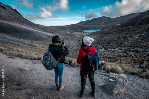 Girl scouts looking at the landscape and discovering new lands between the mountains, wearing winter clothes, where there is snow and the clouds touch the mountain tops photo