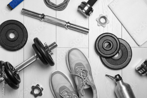 Gym equipment and shoes on wooden floor, flat lay