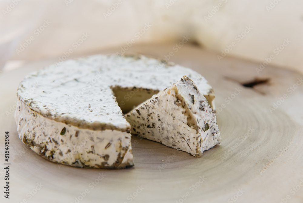 Handmade brie cheese in herbs on wooden table Handmade brie cheese in herbs on wooden table