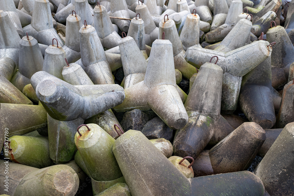 Concrete fortifications in the seaport. Tetrapods stacked on the edge of a breakwater in Central Europe.