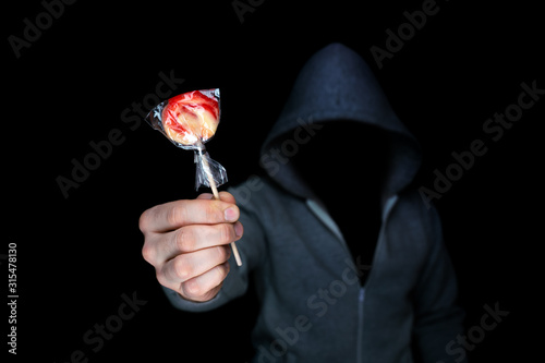 Unknown man holds out candy on a stick.