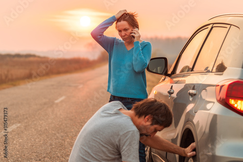 Couple repairing car flat tire on the road © Bits and Splits