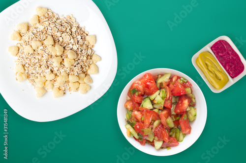 Healthy breakfast on a white plate on a colored background. Muesli with vegetable salad top view photo