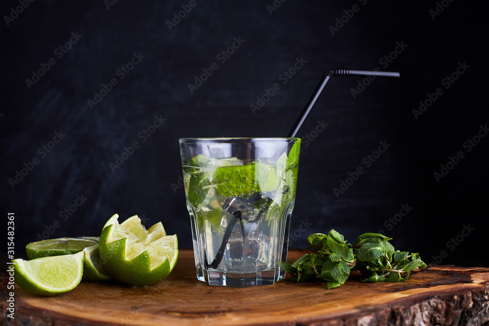 Fototapeta premium Fresh drink with lime, mint and ice on wooden table on dark background