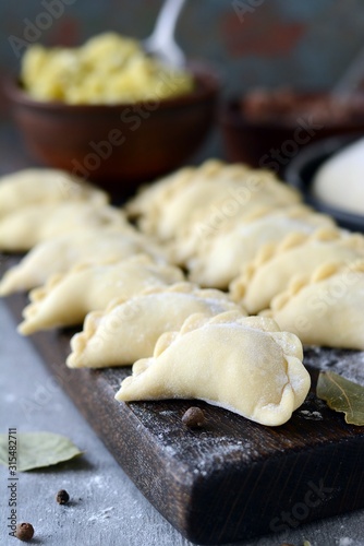 Dumplings with potatoes with herbs on a blue background. Varenyky, vareniki, pierogi, pyrohy - dumplings with filling.