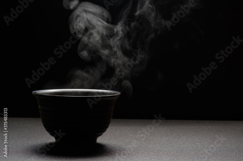 Soup hot in black bowl on wooden table,food steam and copy space ,selective focus.Fresh foods concept