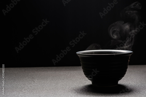 Soup hot in black bowl on wooden table,food steam and copy space ,selective focus.Fresh foods concept