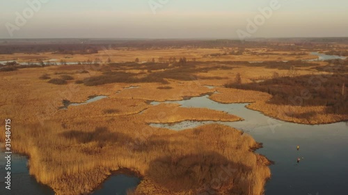 Aerial View Of Forest Woods And Partly Frozen River Landscape In Sunny Late Autunn Day. Top View Of Beautiful European Nature From High Attitude In Autumn Season. Drone View. Bird's Eye View photo