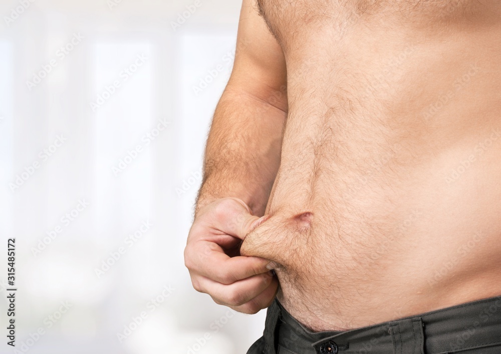 Naklejka premium Slim male figure holding his stomach on grey background
