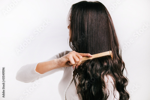 girl combing tangled hair with comb isolated on a white background