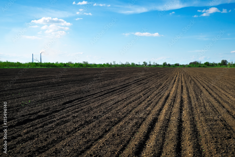 Preparing field for planting. Plowed soil in spring time, two tubes and blue sky.