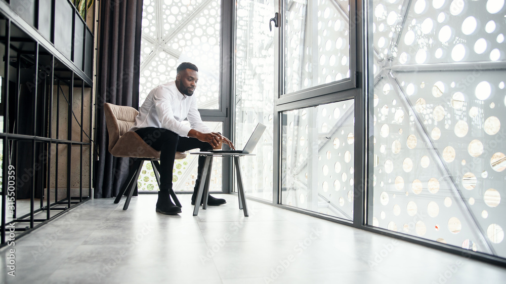 Φωτογραφία Handsome afro american businessman working at the laptop and analysis in the specially designated room in modern stylish office