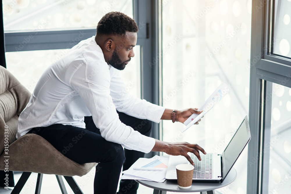 Φωτογραφία Handsome afro american businessman working at the laptop and analysis in the specially designated room in modern stylish office