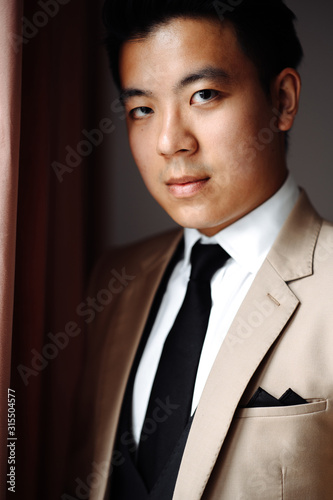 Portrait of an attractive serious asian guy in formal suit, indoors