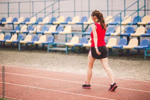 Woman Running At Stadium. Young woman running during on stadium track. Goal achievement concept. Fitness Jogging Workout on ballpark. Wellness theme. Sporty training cardio for weight loss success © Elizaveta