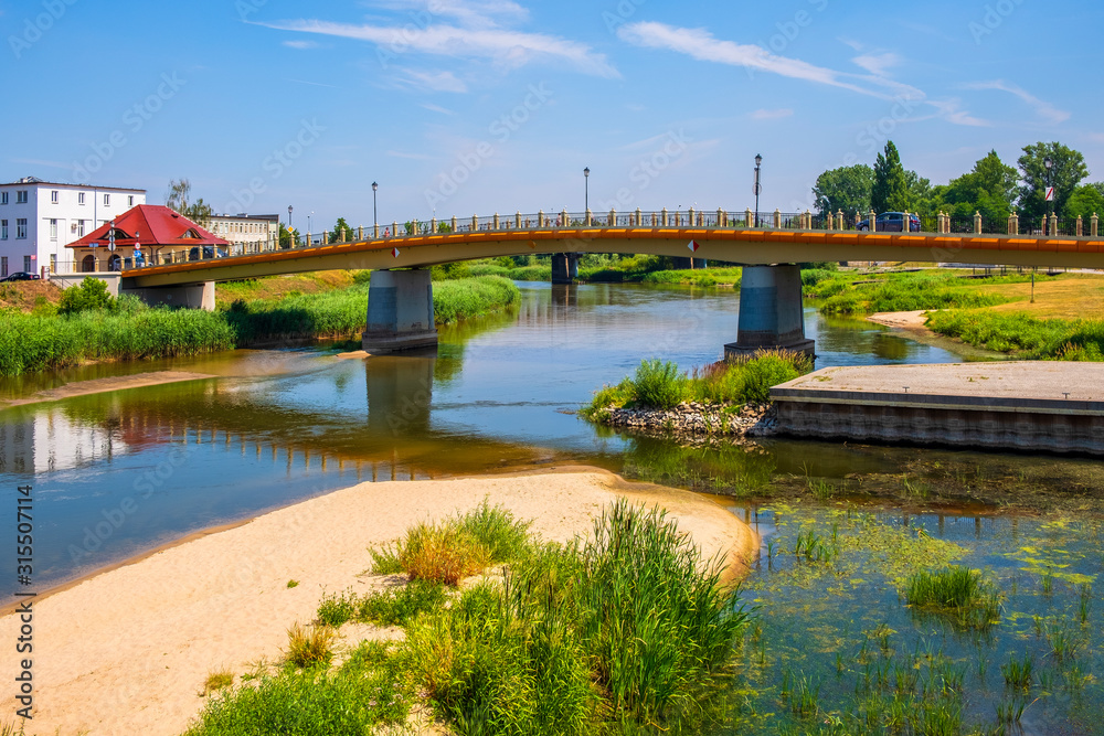 Promenade along the Warta river bank with Torunski bridge in the historic quarter of Konin, Poland
