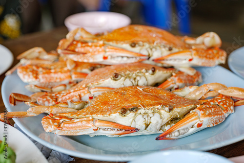 Heap of steamed fresh blue crabs serve on plate with spicy seafood sauce on side. © Peeradontax