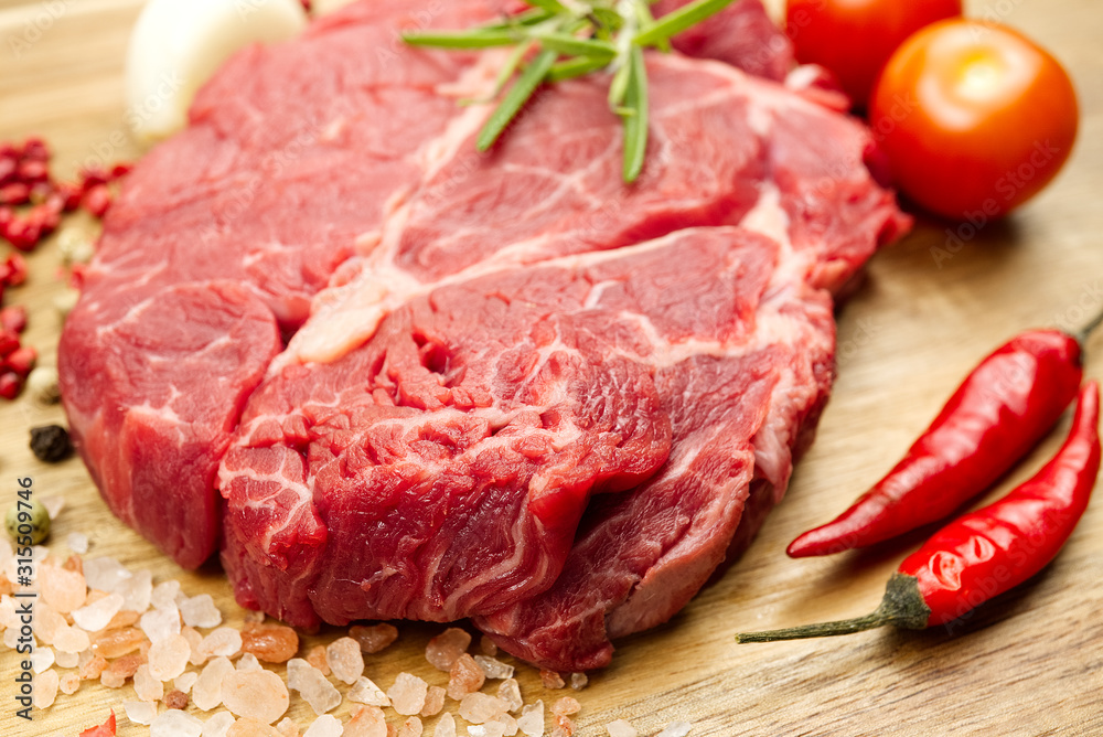 Raw beef steaks on wood board view from above. fresh steak with spices ready for cooking.