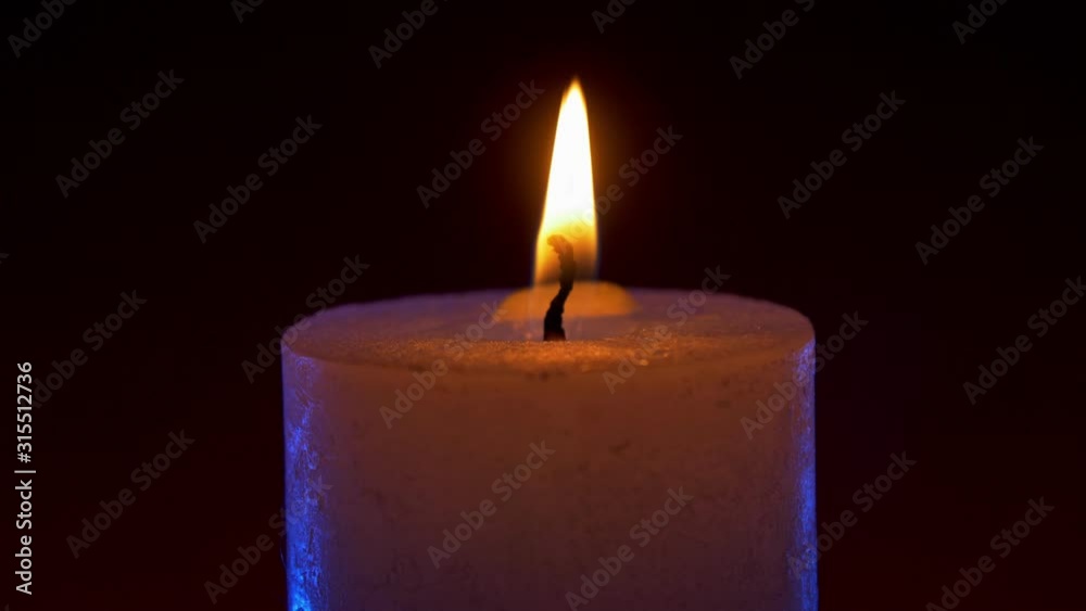 Wide white candle flame on black background with blue rim light Wide white candle flame on black background with blue rim light