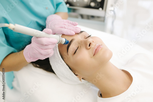 Close-up of woman getting facial hydro microdermabrasion peeling treatment. Female at cosmetic beauty spa slinic. Hydra vacuum cleaner. Cosmetology photo