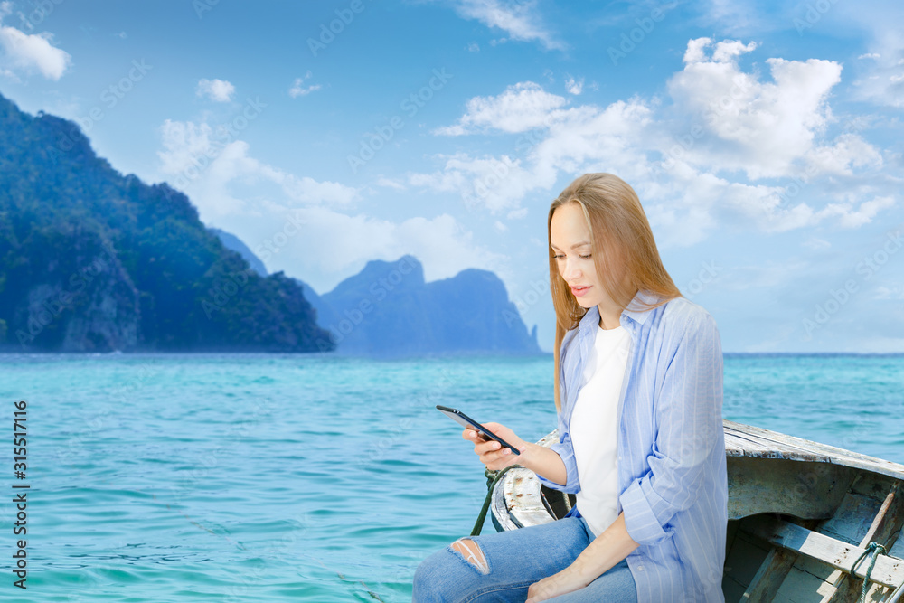 Happy woman using a smart phone  on vacation in a tropical island. Young using a mobile smartphone to share a live to friends on social media at turquoise sea.