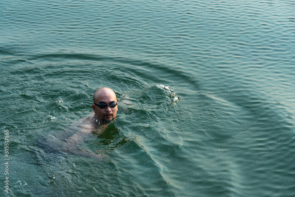 bald adult man swimming in blue nature wave lake summer vacation background