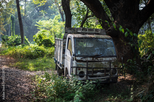 An abandoned van kept in a natural green forest in green background. Indian landscape.