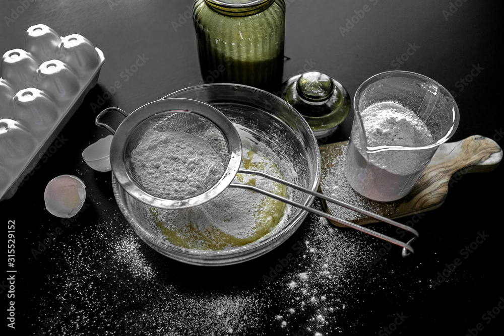 Ingredients for home baking: cookies, bread, cake. Flour, sugar, and eggs are on the black table. Baking dishes. Ingredients for home baking: cookies, bread, cake. Flour, sugar, and eggs are on the black table. Baking dishes.