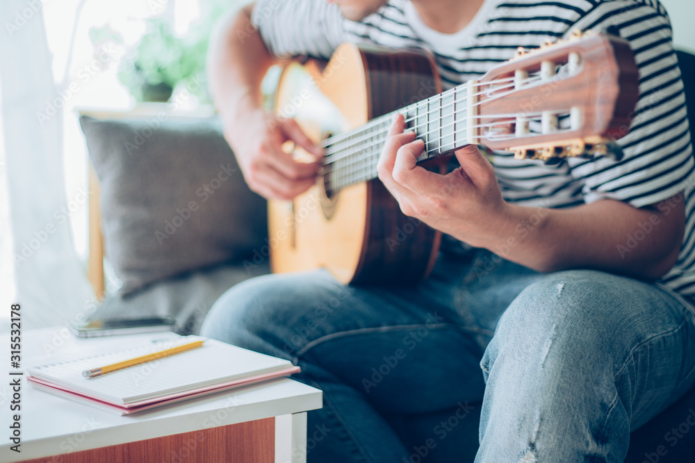 Fototapeta premium artist playing acoustic guitar,sing folk song.happy man sitting enjoy on sofa in relax time.concept for art and music therapy for relaxation and healing for people