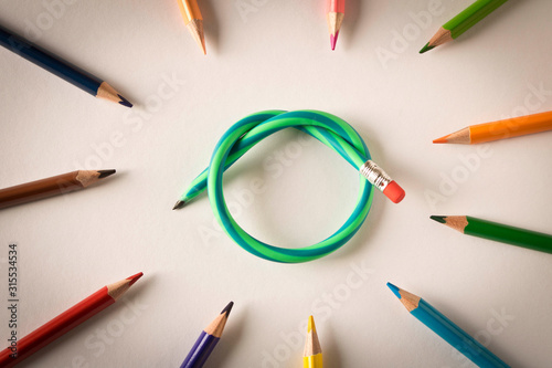 Colored pencils with one flexible pencil on white background. The concept of flexibility in decision-making. photo