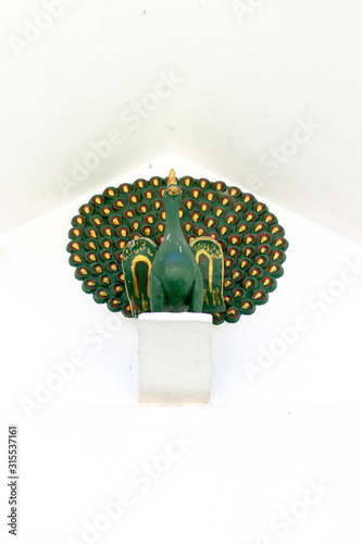 Beautiful peacock statue hanging on white wall background.