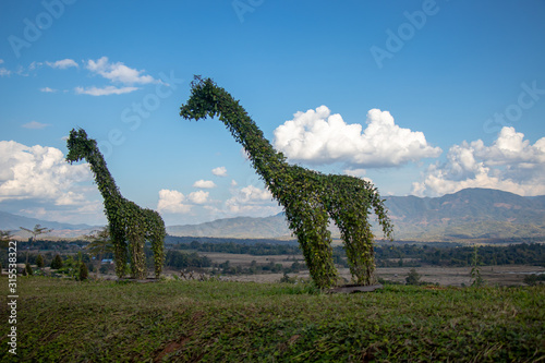 Two giraffe statues made with plants with blue sky background.