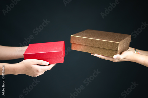 hands hoding gift boxes and exchanging on black background.