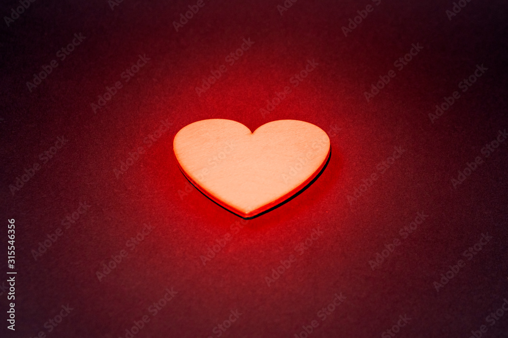 Sparkling golden heart on a dark background. Red backlight, close-up