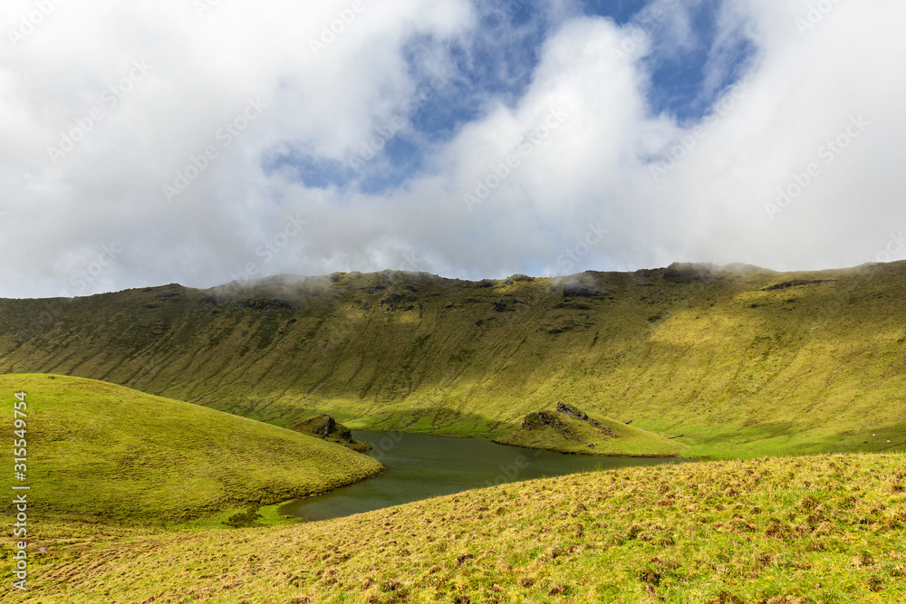 Beautiful greens below blue sky and white clouds in the Corvo caldera on the island of Corvo in the Azores, Portugal.