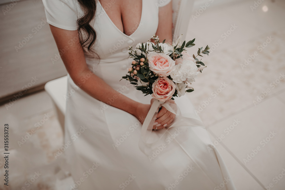 stylish bride without a face in a modest simple white dress holds an incredible bouquet of pink dusty flowers from peony roses and green plants for decoration stylish bride without a face in a modest simple white dress holds an incredible bouquet of pink dusty flowers from peony roses and green plants for decoration