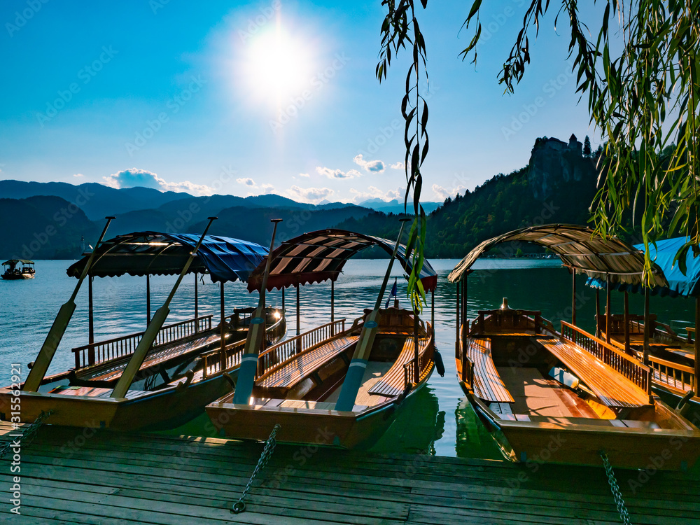wooden tourist boats on Lake Bled in Slovenia during a summer day with the sun