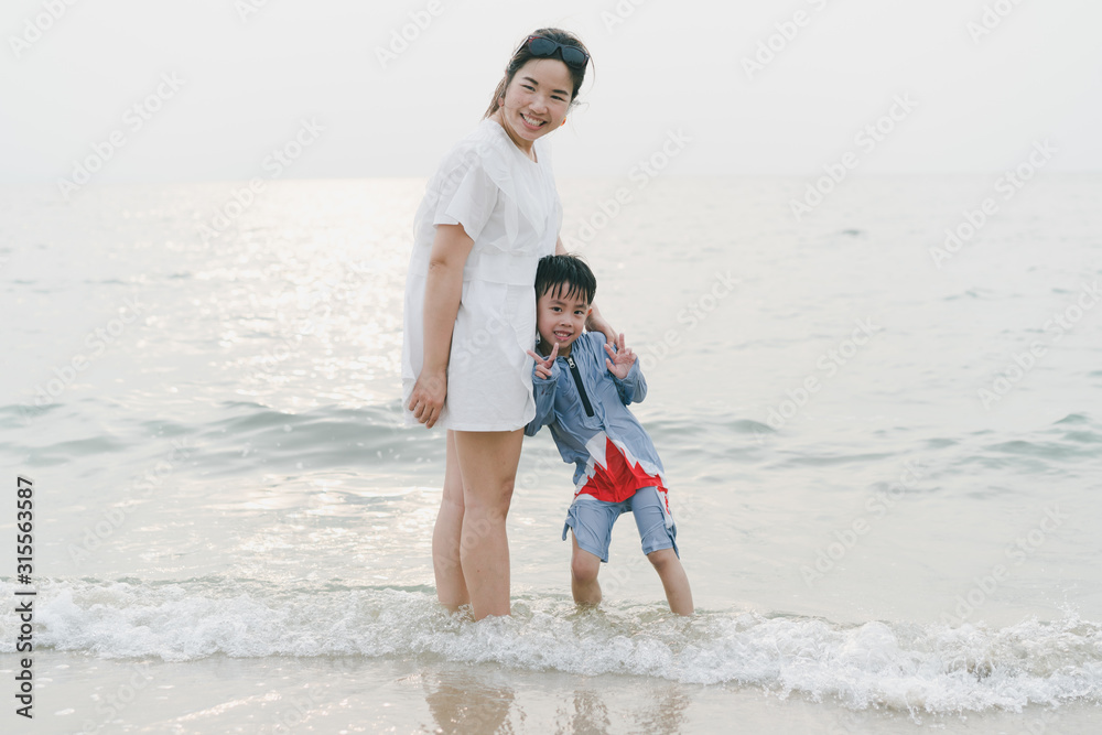 A mother is playing sand and swimming with her son on the beach.