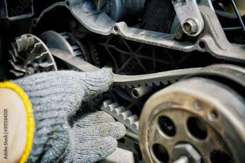 Obraz na płótnie mechanic check the condition of motorcycle or big scooter drive belt .Check the belt tension at motorcycle garage.repair and maintenance motorcycle concept.selective focus w salonie