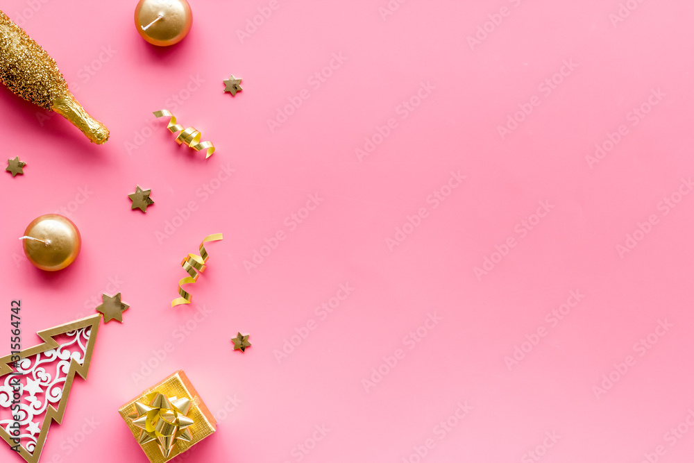 New Year symbols - tree, champagne, decorations - on pink background top-down frame copy space