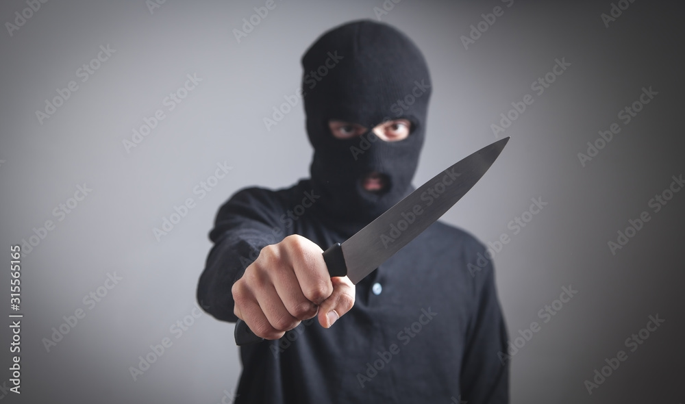 Man in black balaclava threatening with knife. Man in black balaclava threatening with knife.
