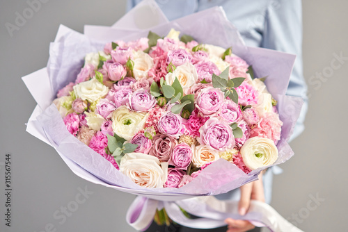 European floral shop. Beautiful bouquet of mixed flowers in womans hands. the work of the florist at a flower shop. Delivery fresh cut flower.