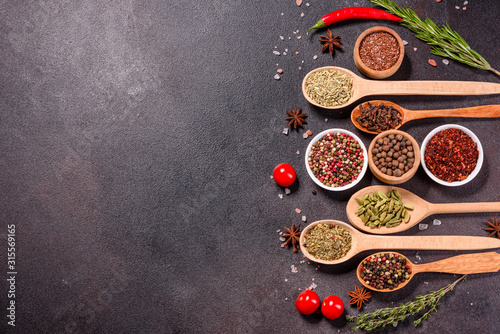 A set of spices and herbs. Indian cuisine. Pepper, salt, paprika, basil and other on a dark background